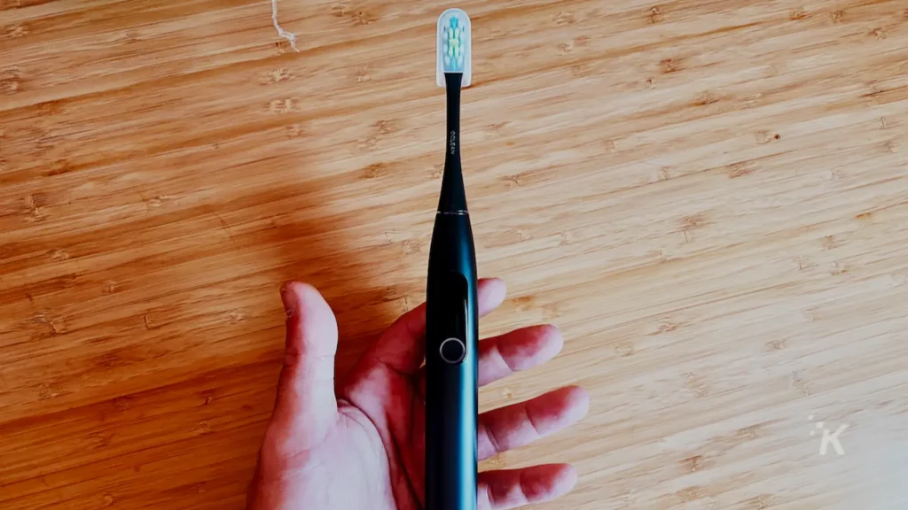 brosse à dents électronique à la main sur un bureau en bois