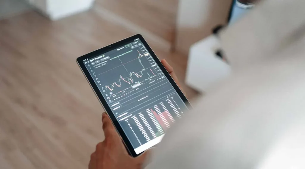 immagine di una persona con in mano un tablet che visualizza un'app di trading/investimento/cripto