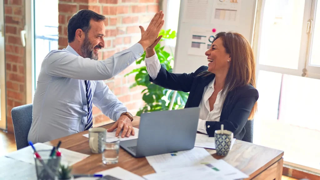 dua orang di kantor teknologi bisnis high five