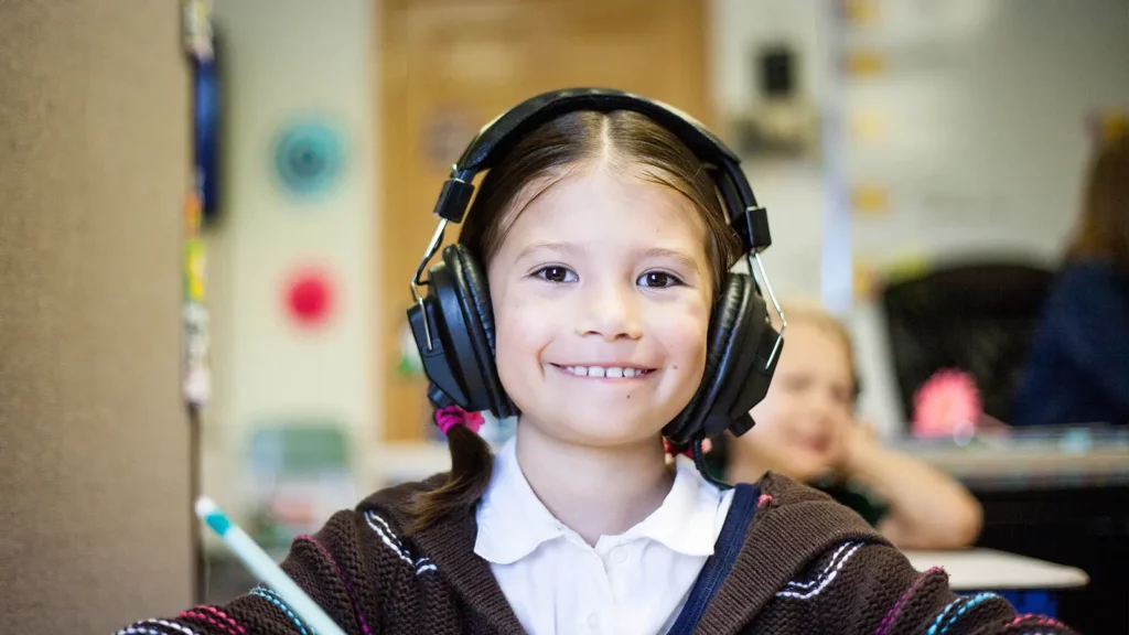 niño escuchando audiolibro con auriculares tutoría en línea