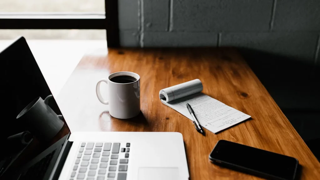 telefono del blocco note della tazza di caffè del computer portatile sulla scrivania di legno