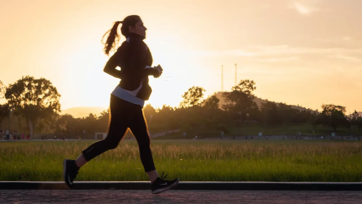 femeie care face jogging la apus