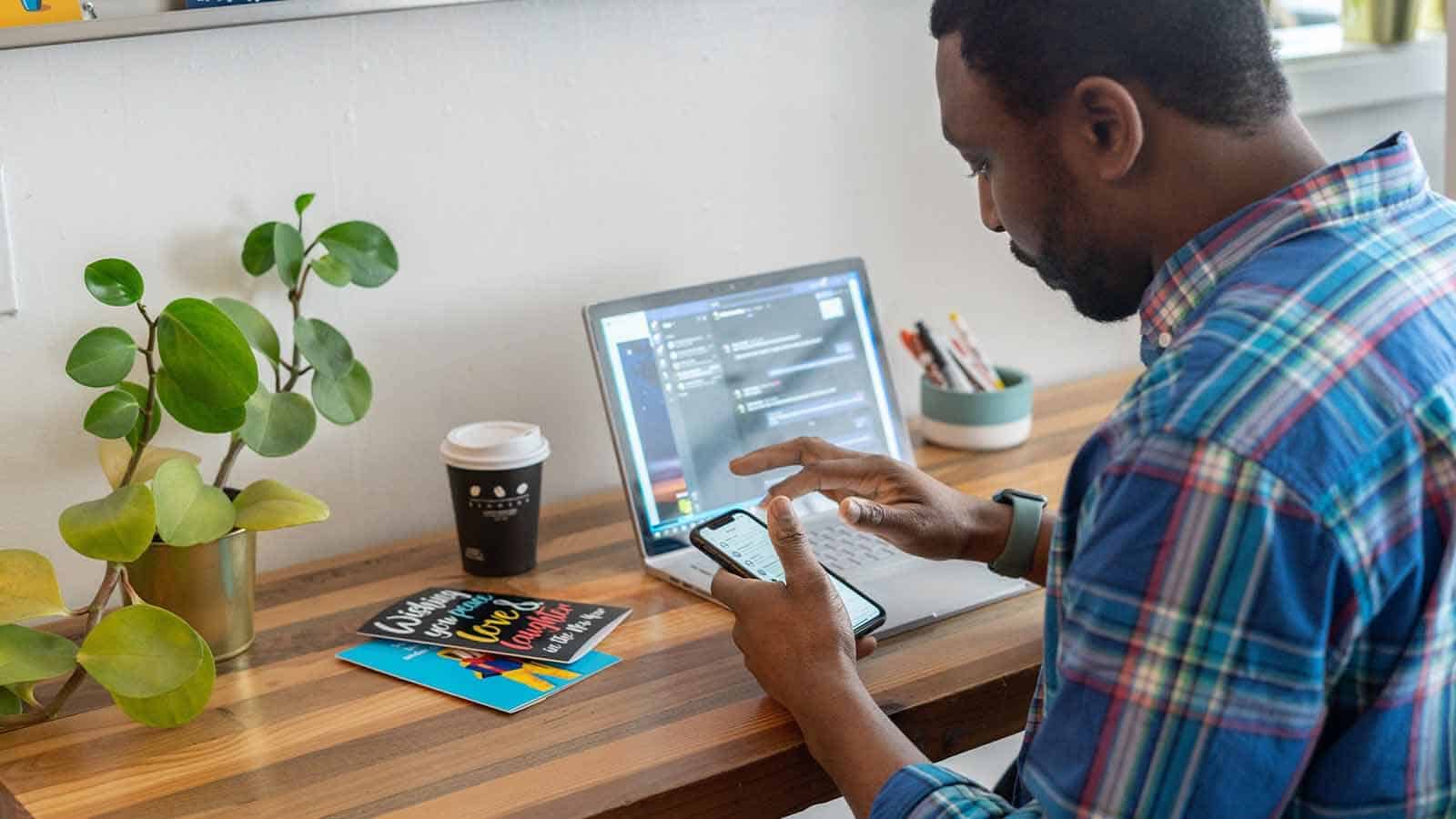 homme regardant son téléphone devant son ordinateur