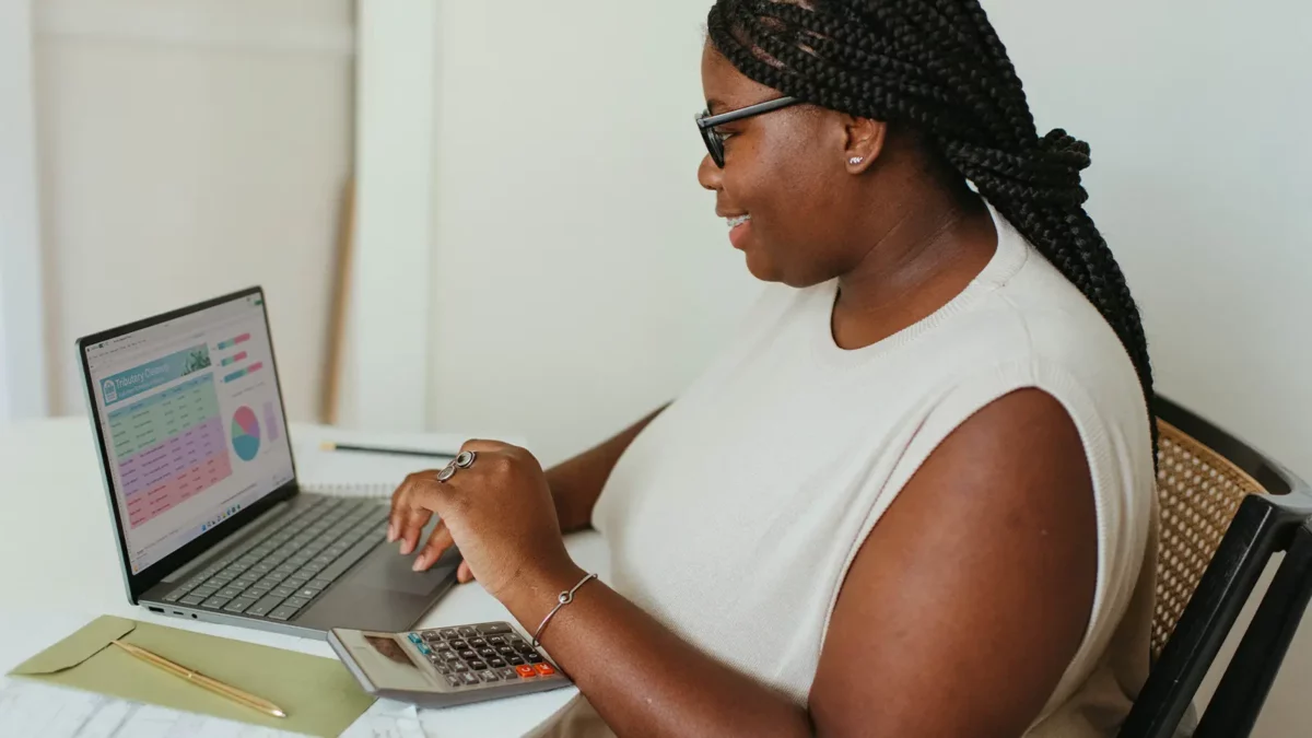 signora seduta davanti a un computer portatile che visualizza grafici mentre esegue il lavoro a distanza