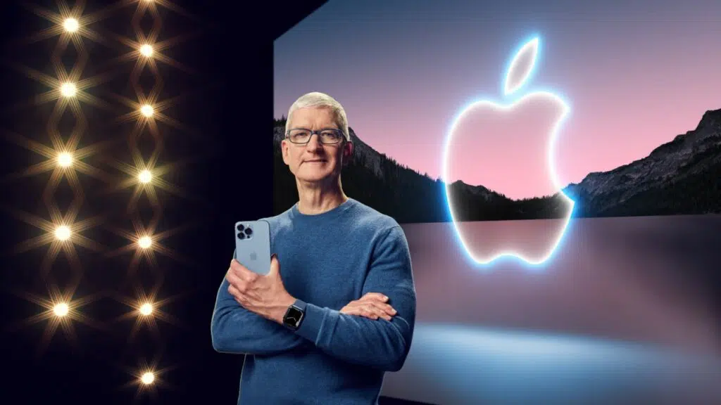dyrektor generalny firmy apple, Tim Cook, stojący na scenie, trzymający iPhone'a i noszący zegarek firmy Apple