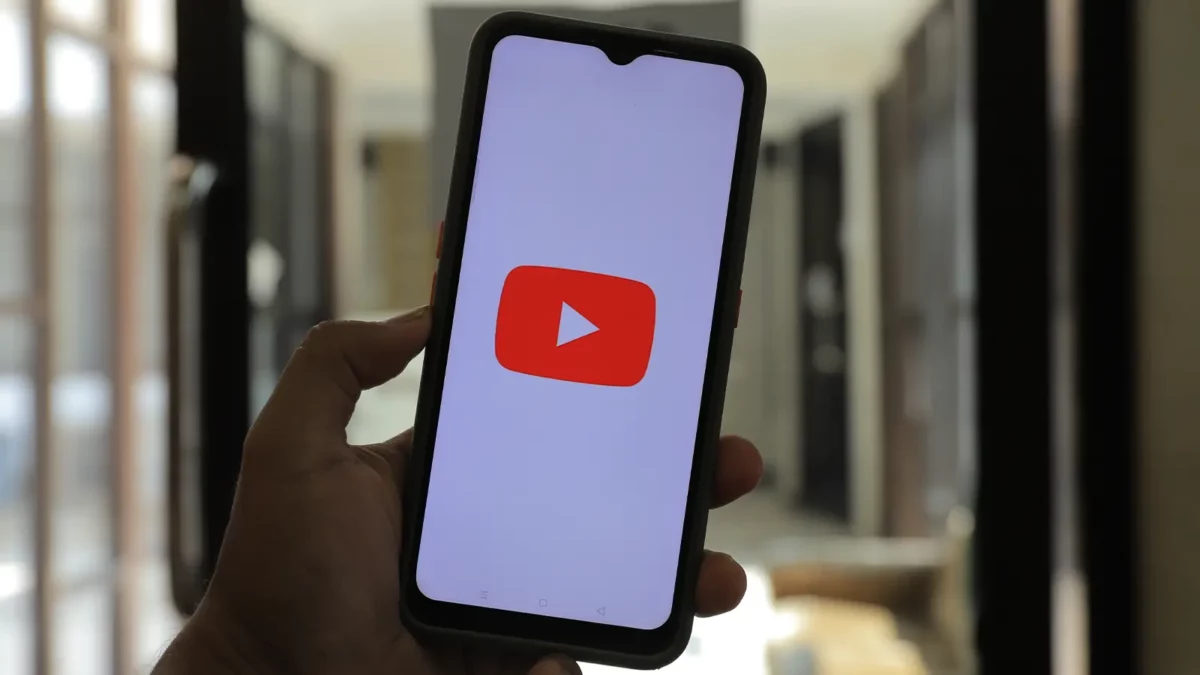 Pessoa segurando um telefone com o logotipo do YouTube na tela.