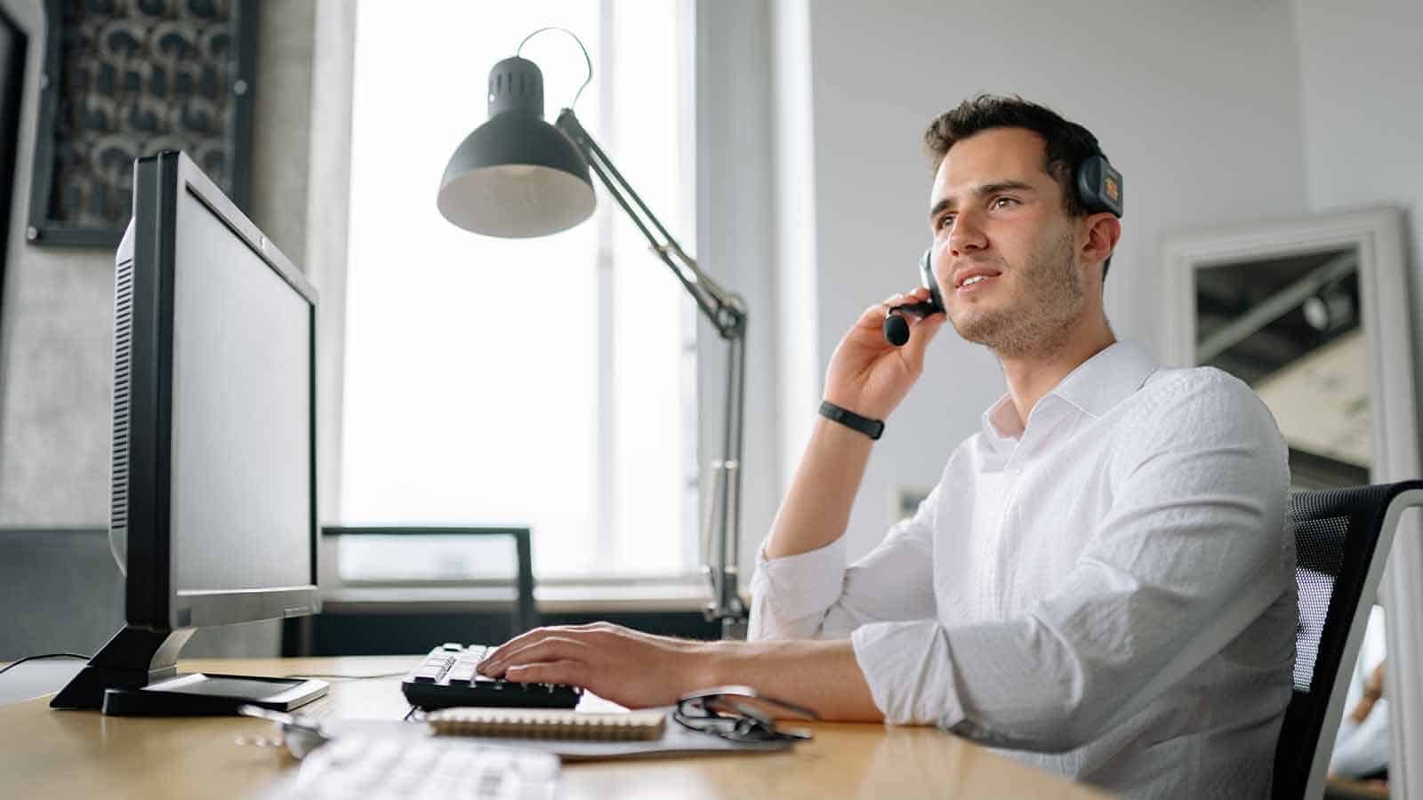 bărbat la birou care oferă asistență pentru clienți prin telefon