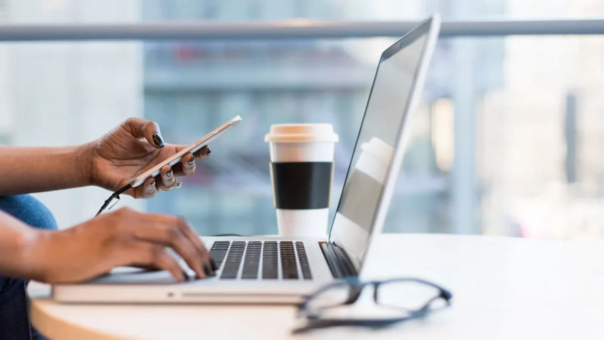 mains sur le clavier et le téléphone d'un ordinateur portable