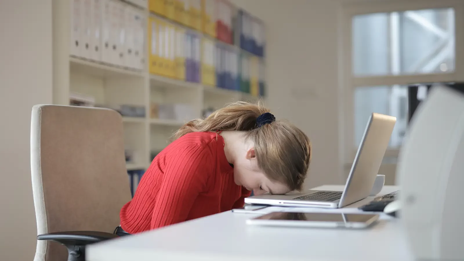 mujer con la cabeza en una laptop