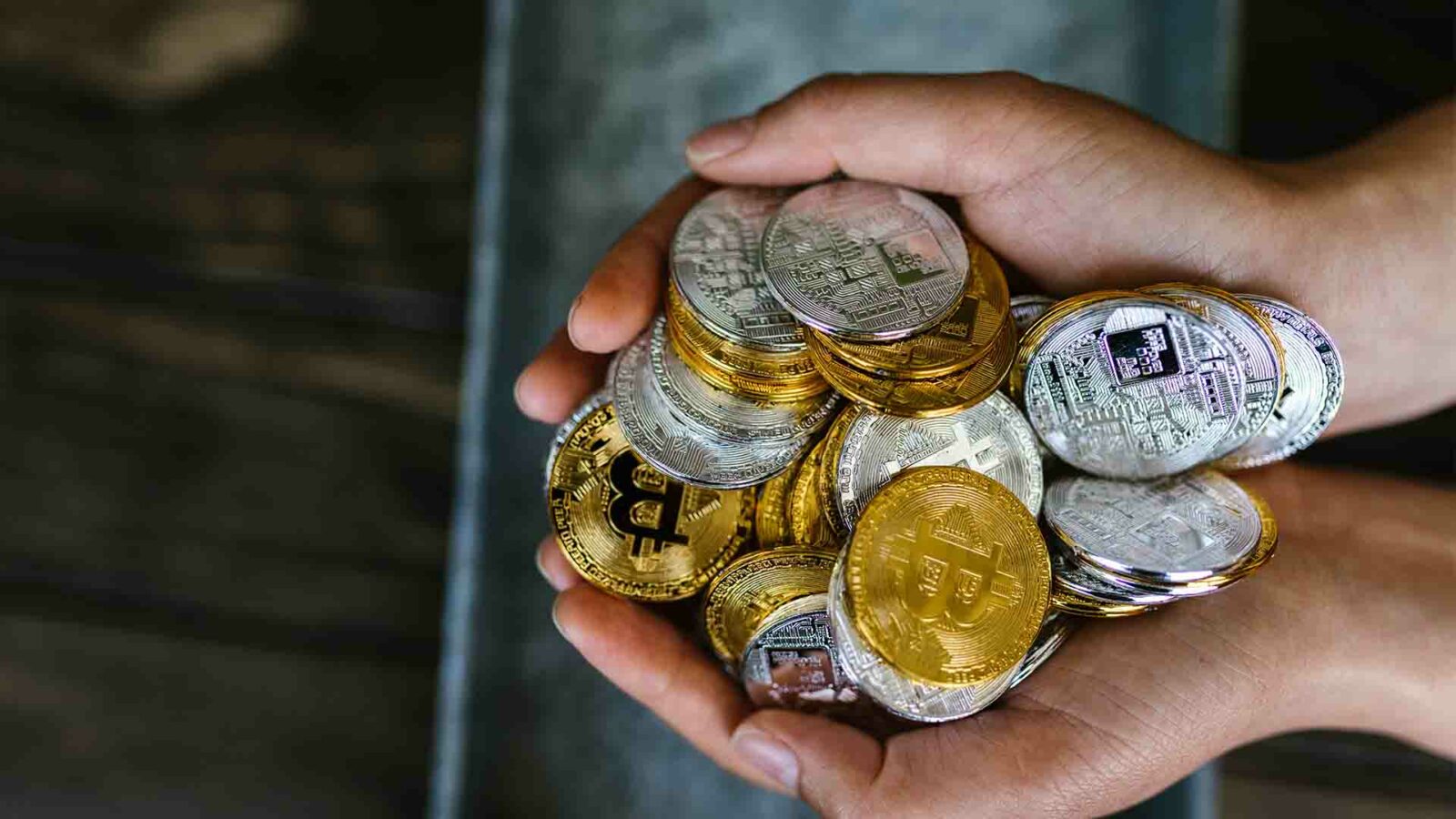 Uma pessoa está lidando com bitcoins e dinheiro enquanto um prego de metal mantém a moeda no lugar.