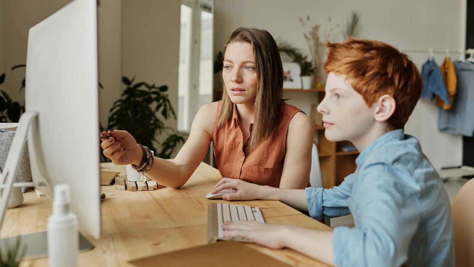 Due persone siedono a un tavolo e guardano un computer.