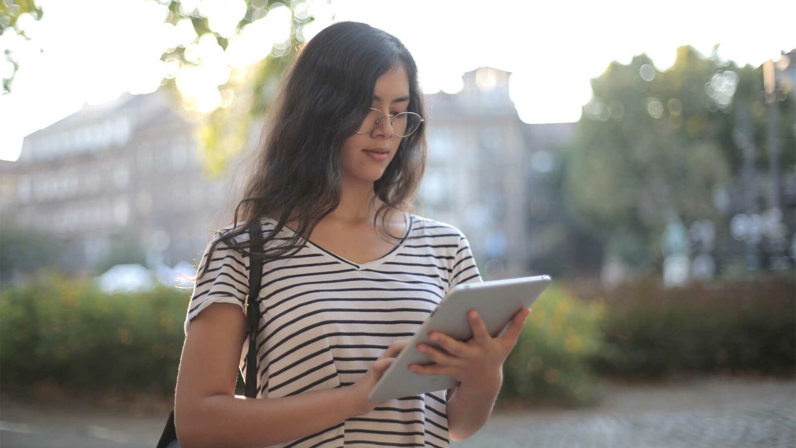 Une personne tient une tablette à l'extérieur.