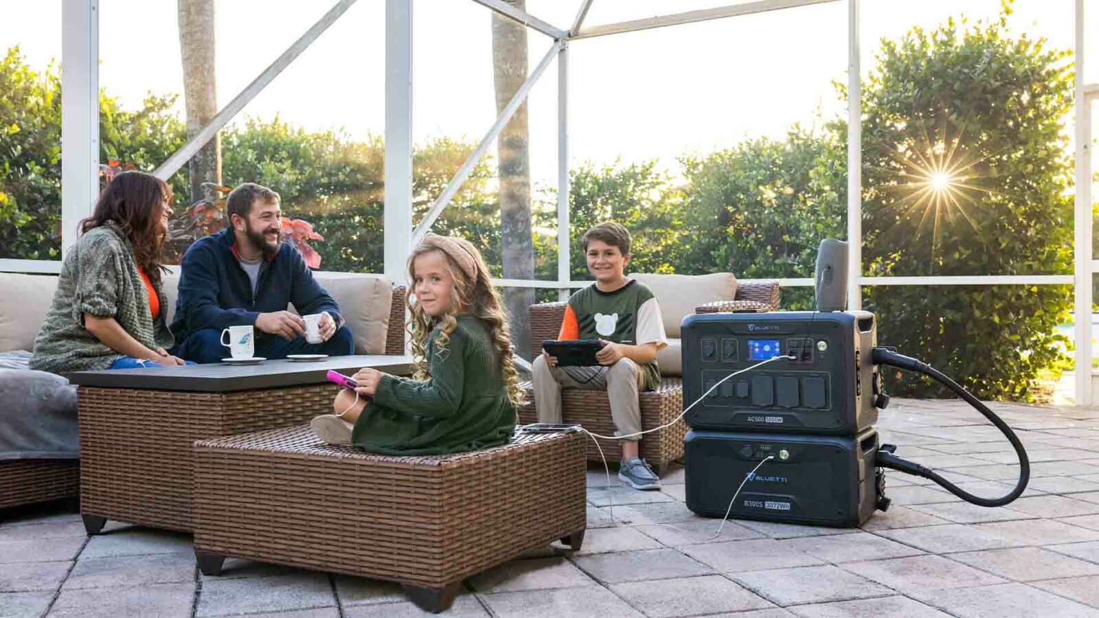 Eine Gruppe sitzt auf einer Terrasse um einen Tisch und einen Grill.