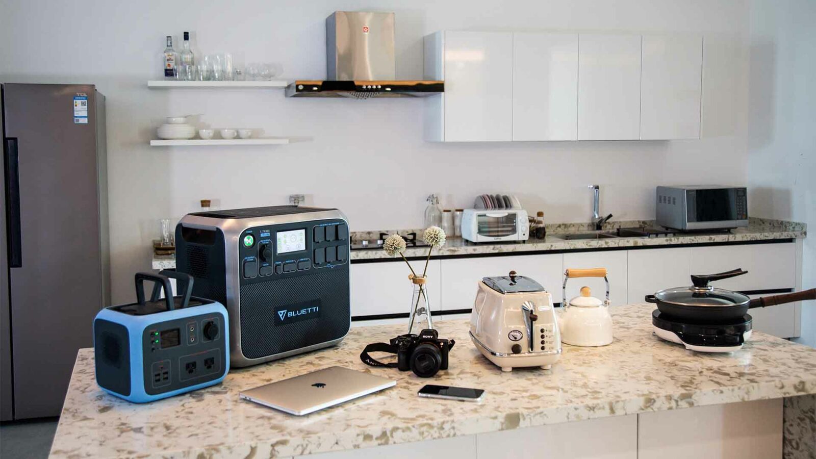 Um fogão a gás, forno de microondas, cafeteira e outros utensílios de cozinha ficam em cima dos armários da bancada, com uma pia e gavetas abaixo, criando um espaço de cozinha funcional.