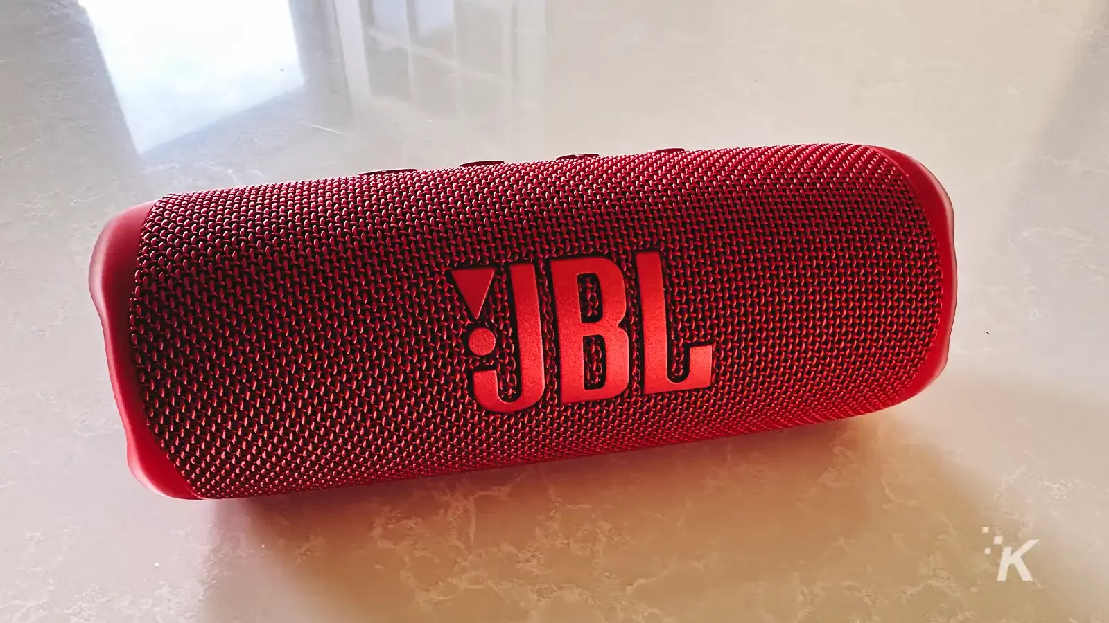 Speaker portabel JBL Flip 6 berwarna merah di atas meja