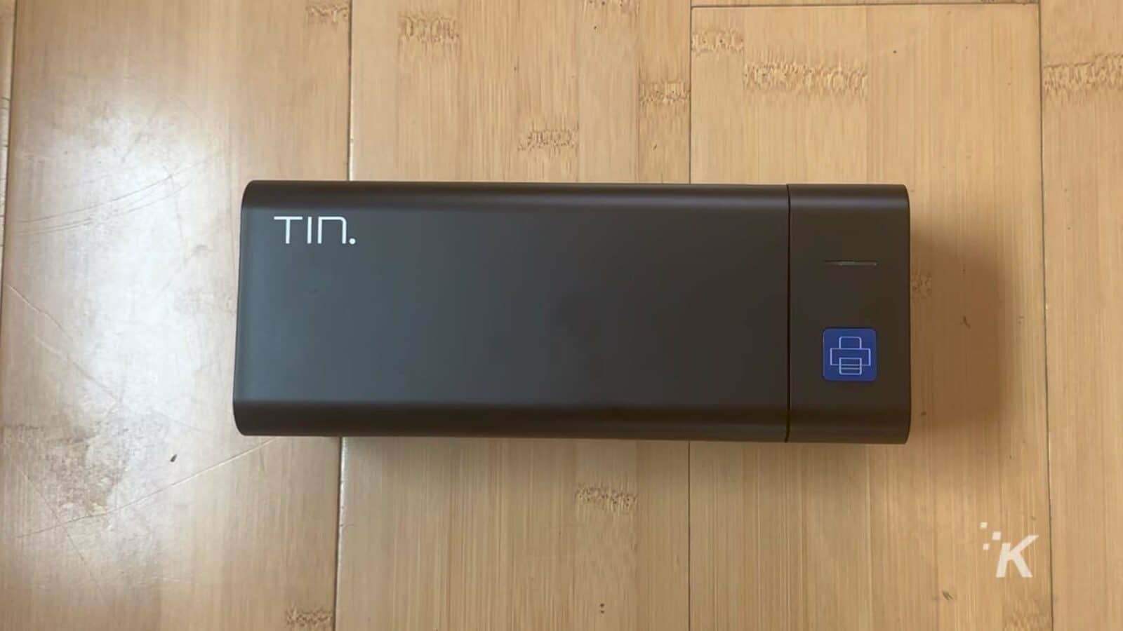 Un dispositivo rectangular negro se asienta sobre una superficie de madera.