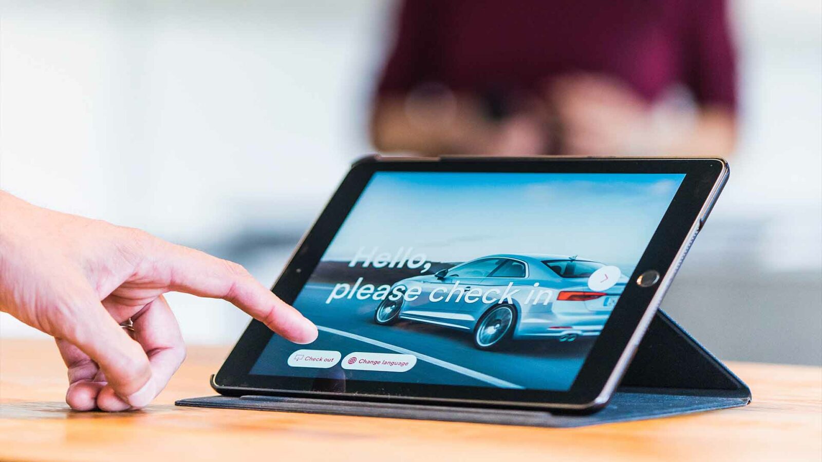 Una persona utilizza un laptop, un tablet, un gadget per auto e un dispositivo di comunicazione portatile su un tavolo all'interno utilizzando il software di gestione della proprietà dell'hotel