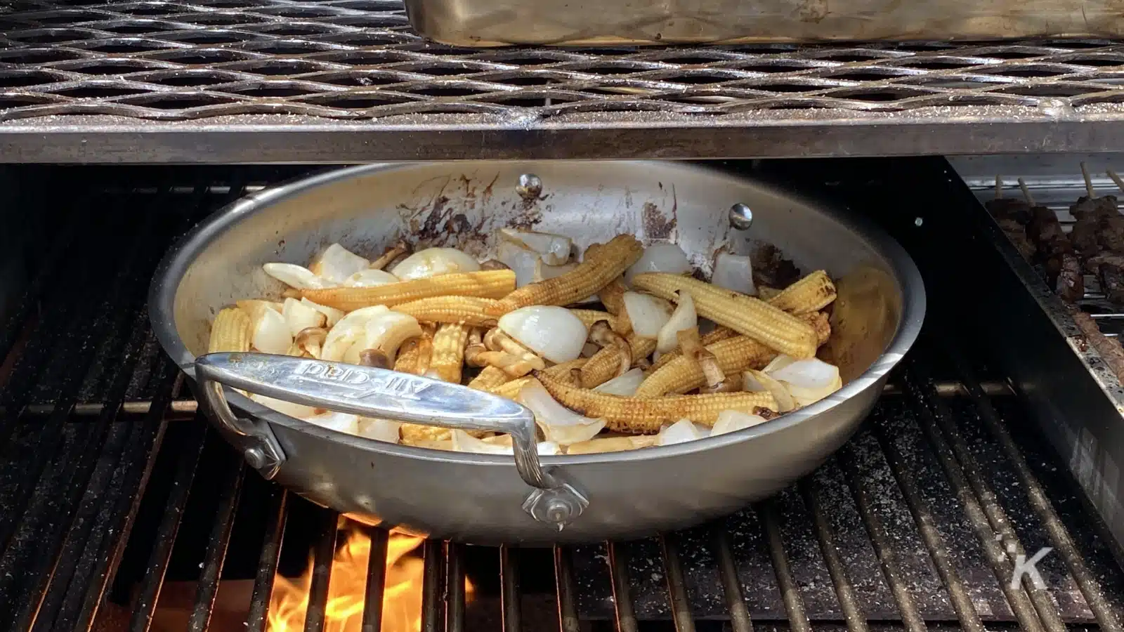 Un cuoco sta grigliando pezzi di pollo e friggendo patatine fritte in una padella di olio bollente sulla griglia di un fast food.