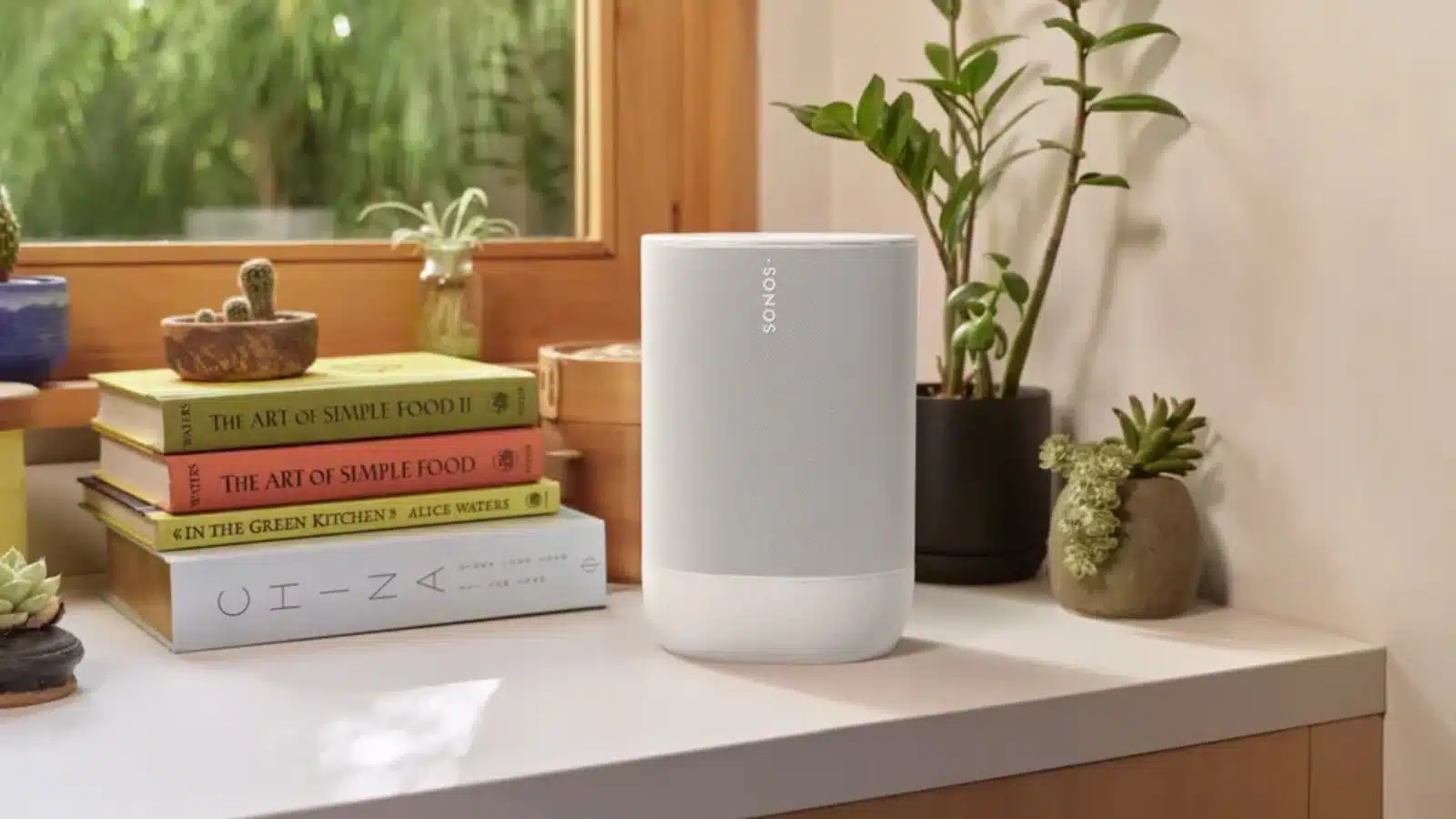 Sonos move 2 speaker in white on a countertop surrounded by books and plants