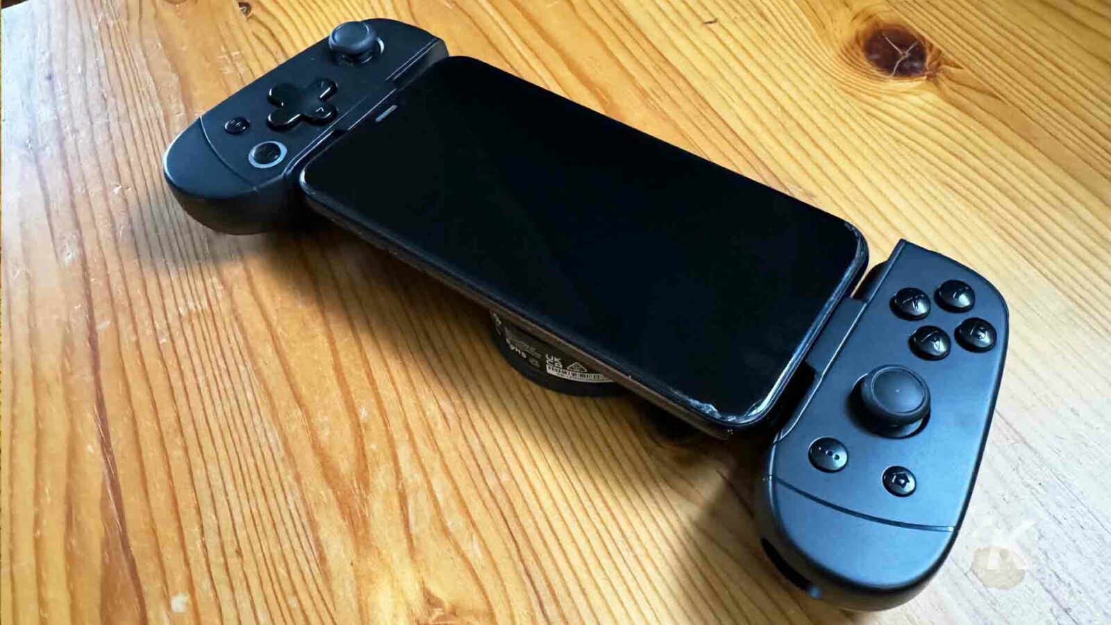 Auf einem Holztisch liegen ein Smartphone und ein Gamecontroller, ein tragbares Kommunikationsgerät für den täglichen Gebrauch.