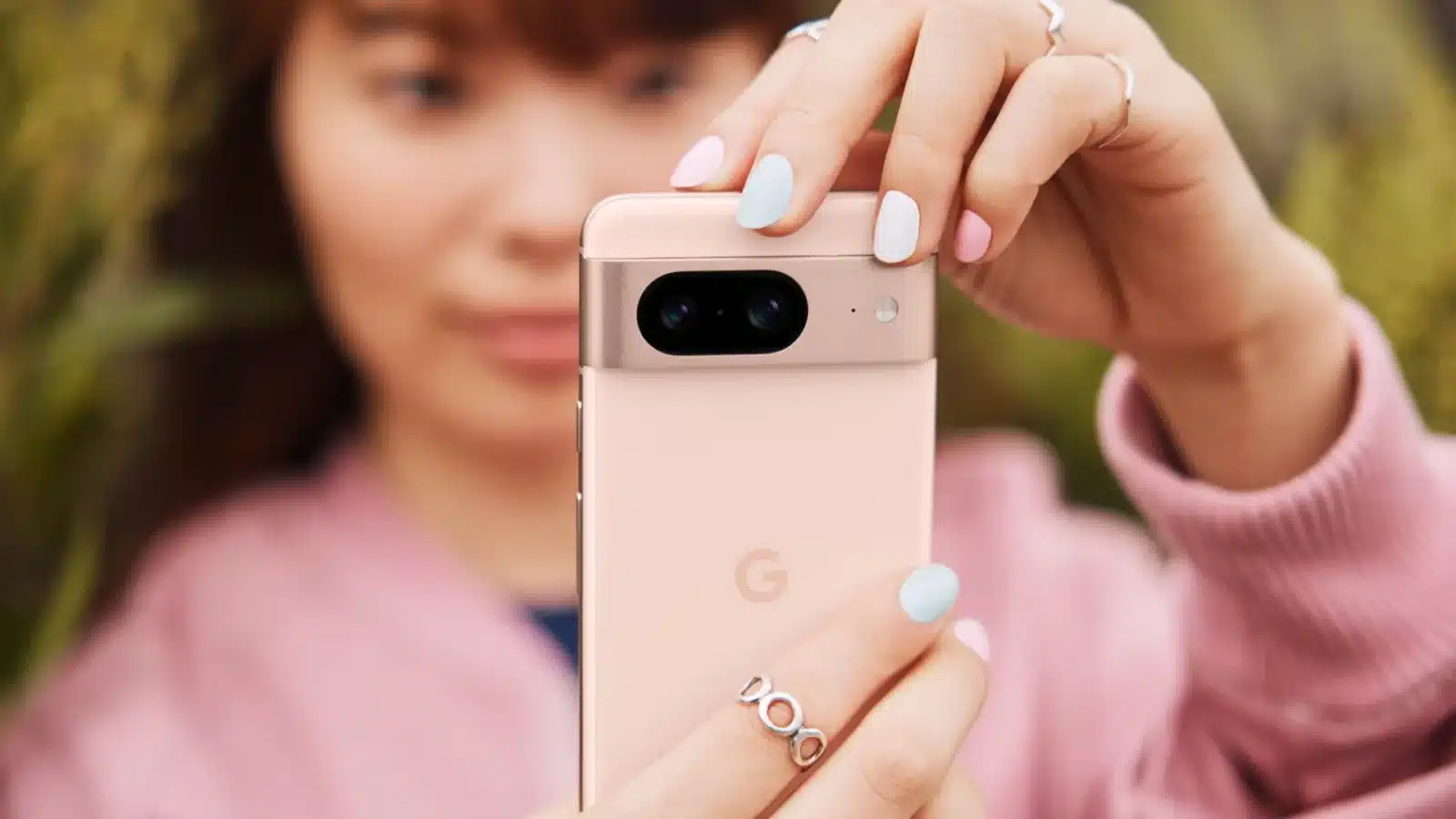 A person holds a google pixel 8 in pink color
