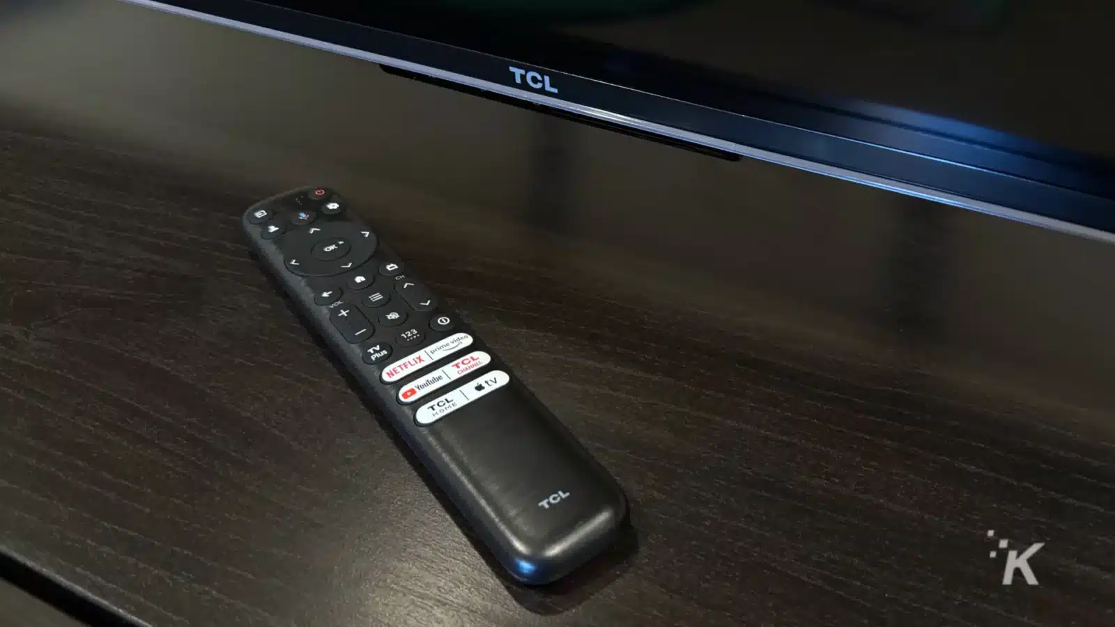 A tcl remote control sits on a table.