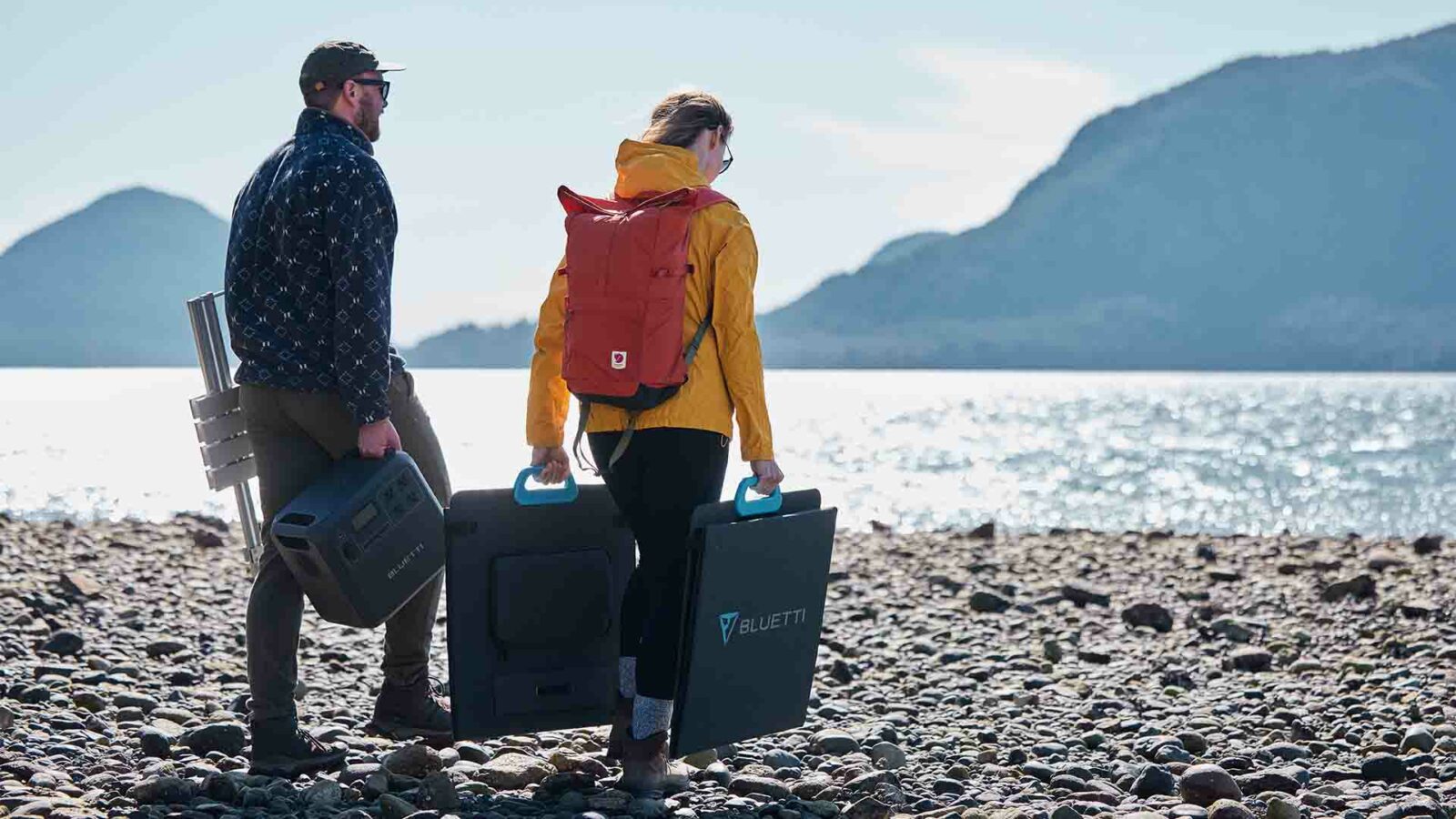 Zwei Personen stehen mit Gepäck am Strand.