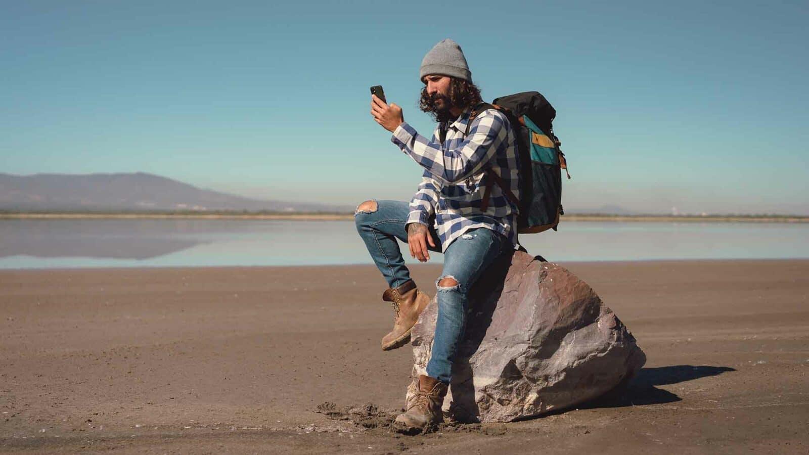 Uma pessoa sentada em uma pedra olhando para seu receptor GPS.