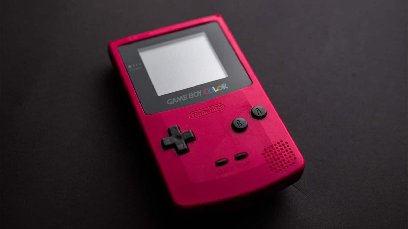 Uma vibrante cor rosa de game boy sobre um fundo escuro, destacando sua tela, botões e a marca Nintendo – jogos portáteis nostálgicos do final dos anos 1990. Jogando nft no gameboy.