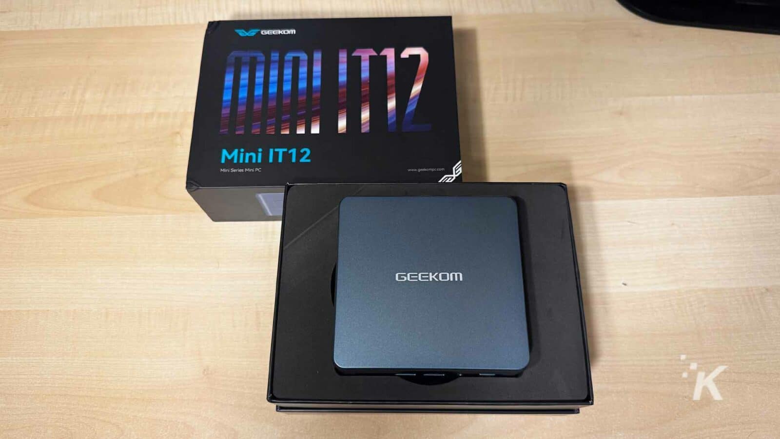 Geekom mini it12 pc în cutie pe un birou din lemn