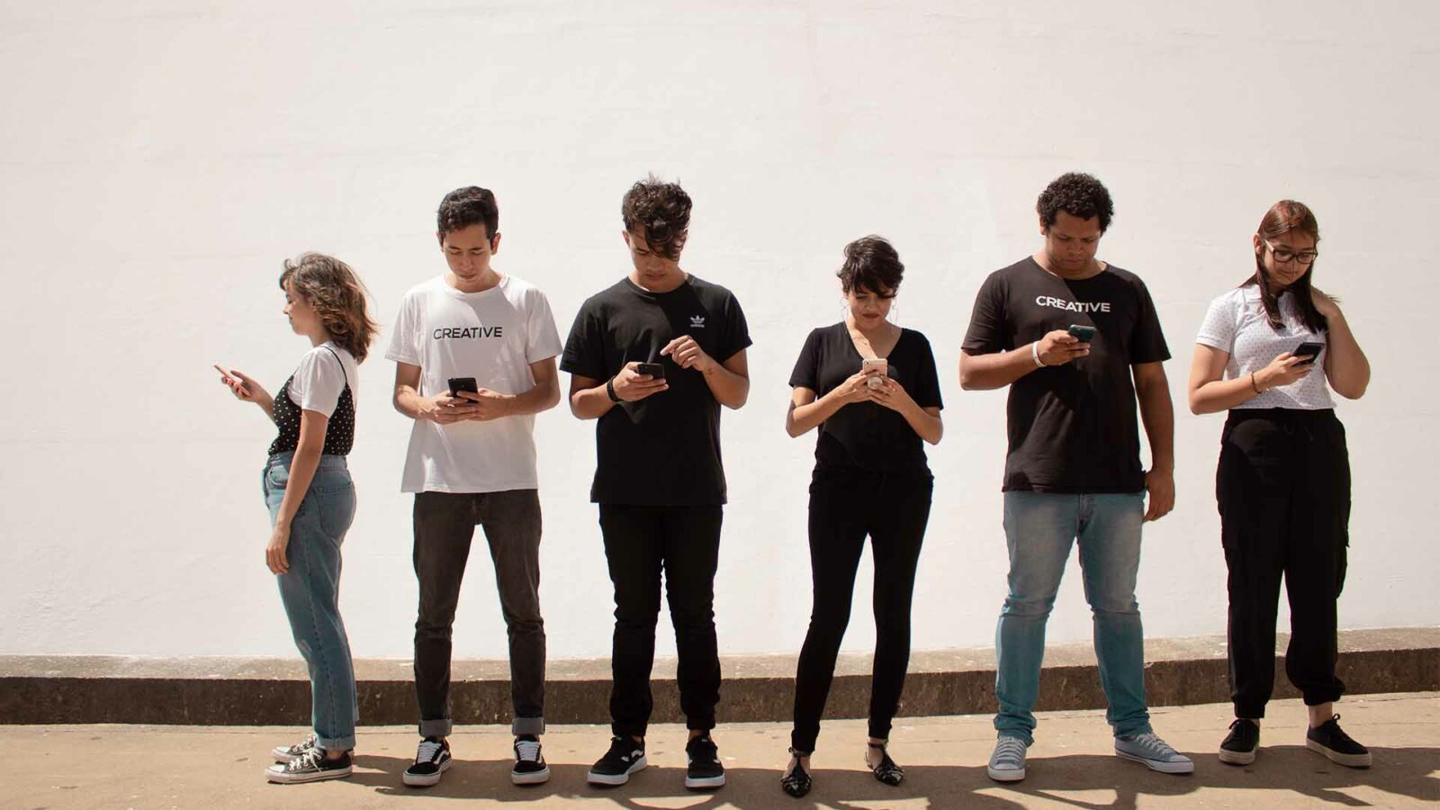 Un gruppo di adolescenti in piedi guardando i telefoni