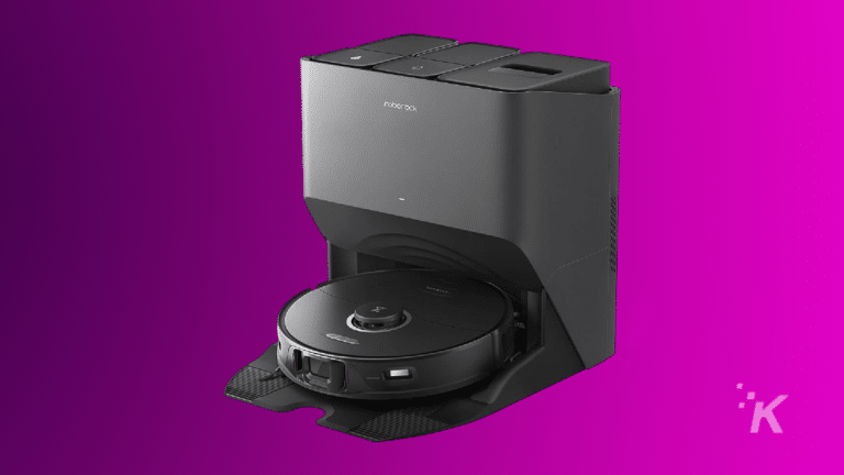 Un aspirateur robot Roborock se connectant à sa station de charge noire sur fond violet.