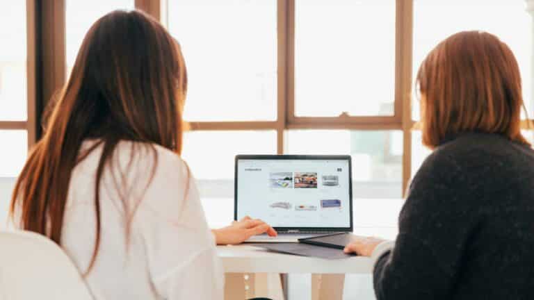 duas mulheres trabalhando em um laptop.