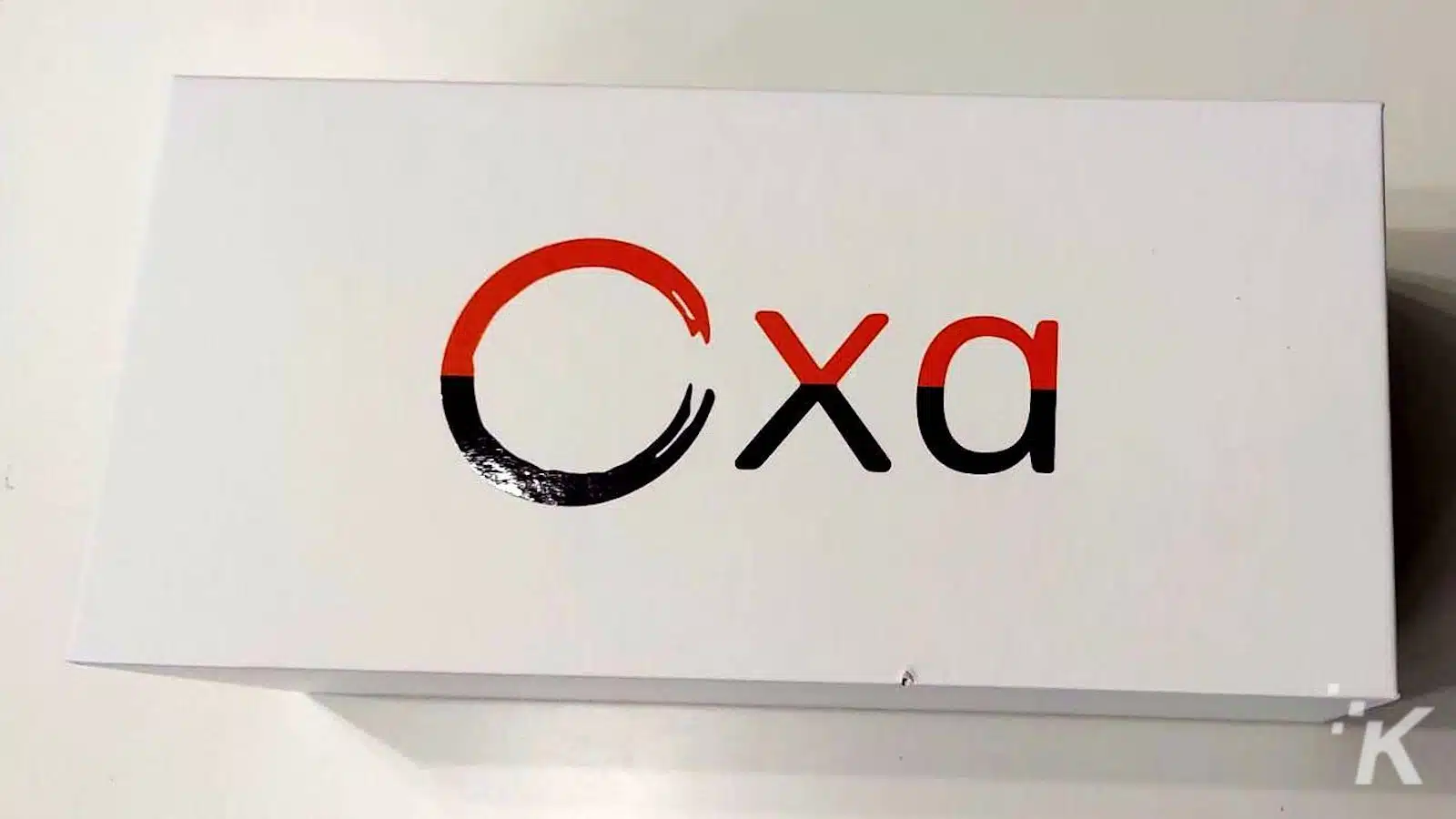 Logo cu literele „Cxa” în negru și roșu.