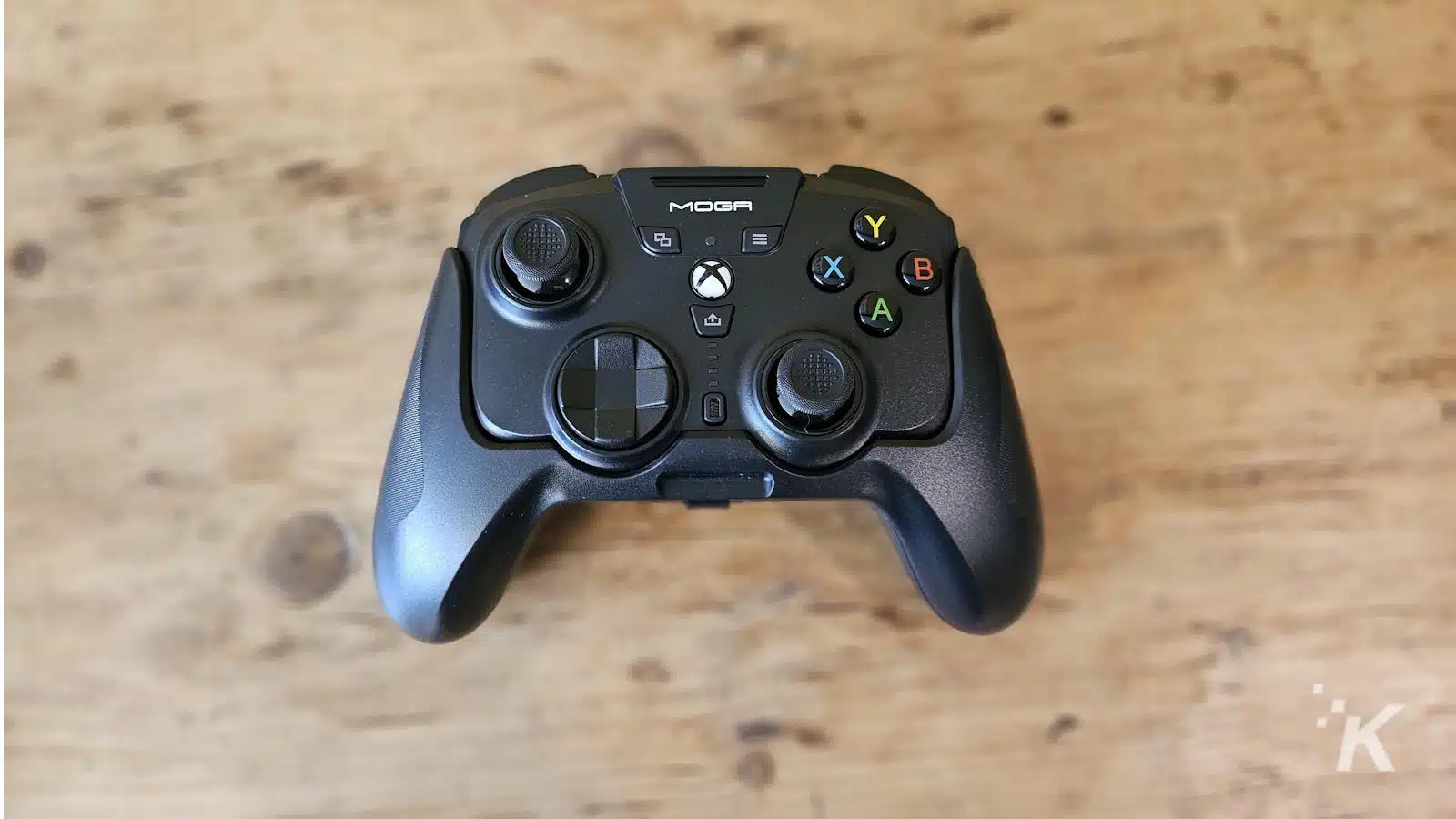 Controlador de jogos Xbox MOGA na mesa de madeira.