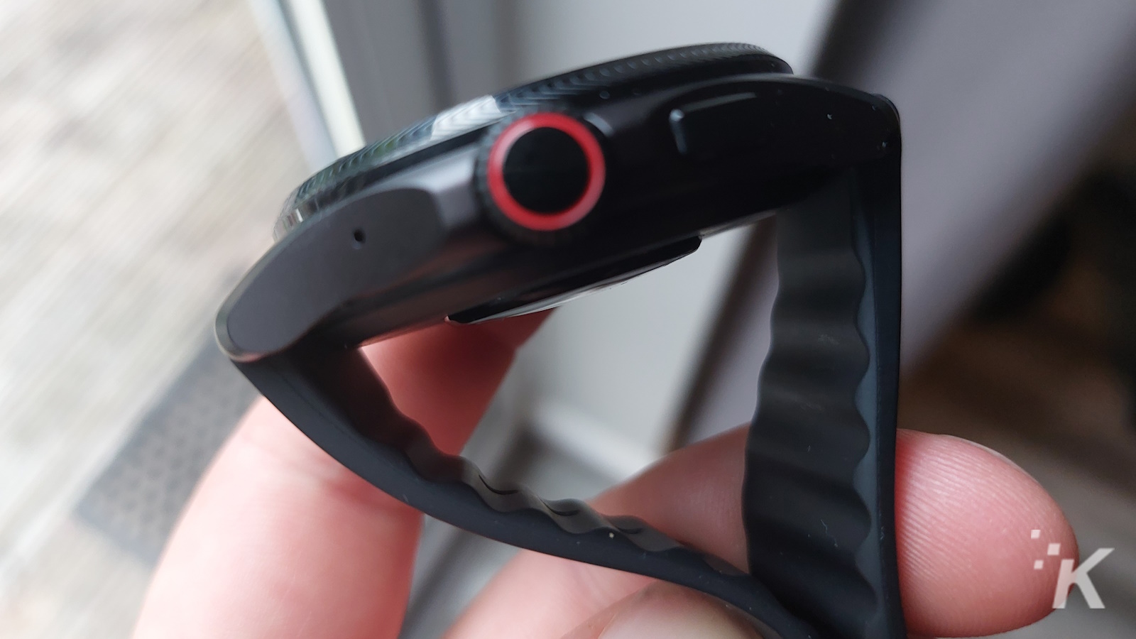 Vista lateral del Smartwatch con banda negra y botón rojo