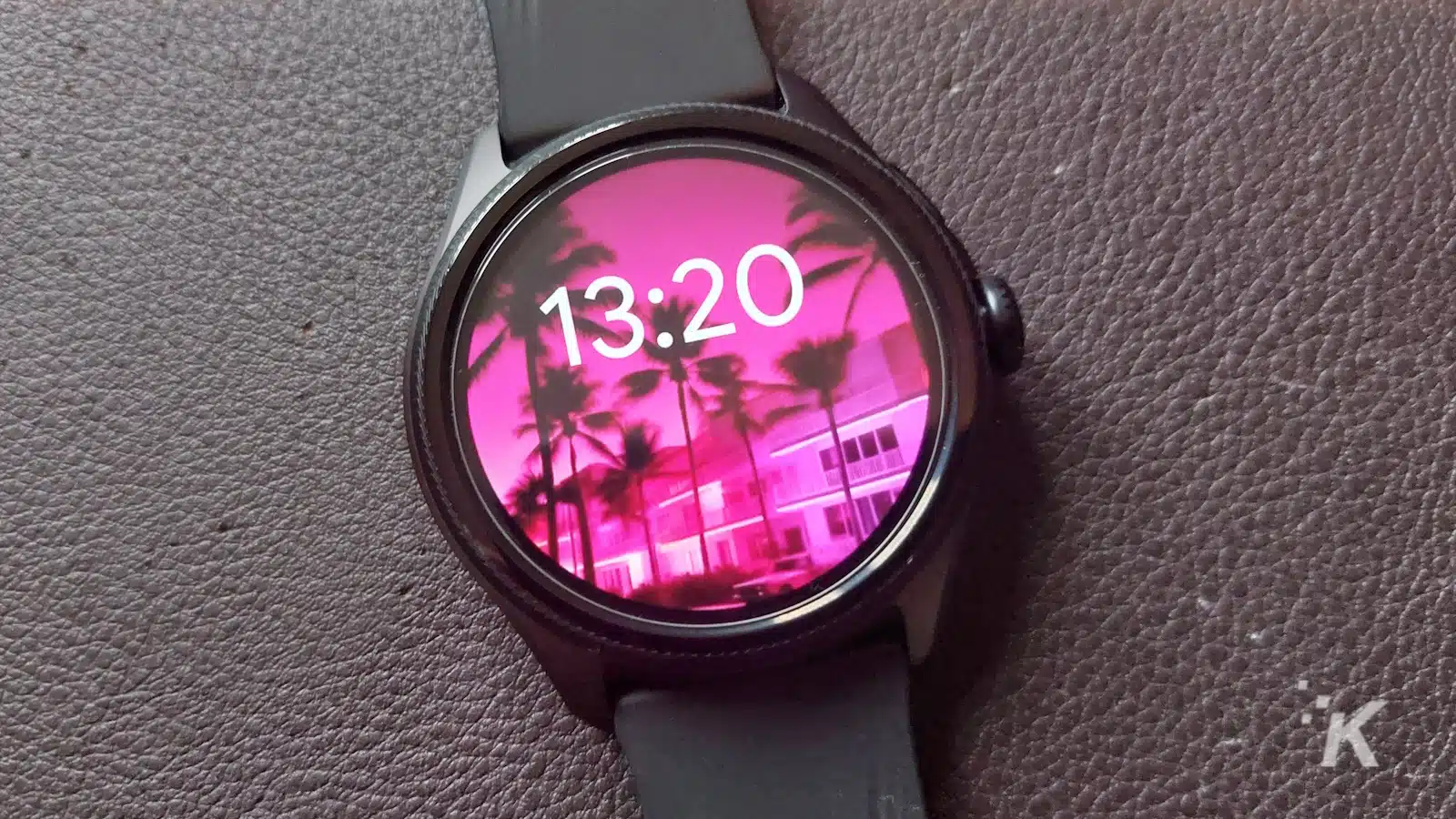 Smartwatch-Display zeigt 13:20 mit rosafarbenem Hintergrund.