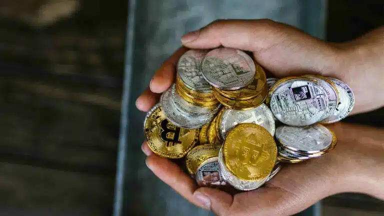 บุคคลหนึ่งกำลังจัดการ bitcoins และเงินสด ในขณะที่ตะปูโลหะยึดสกุลเงินไว้ สกุลเงินดิจิทัล